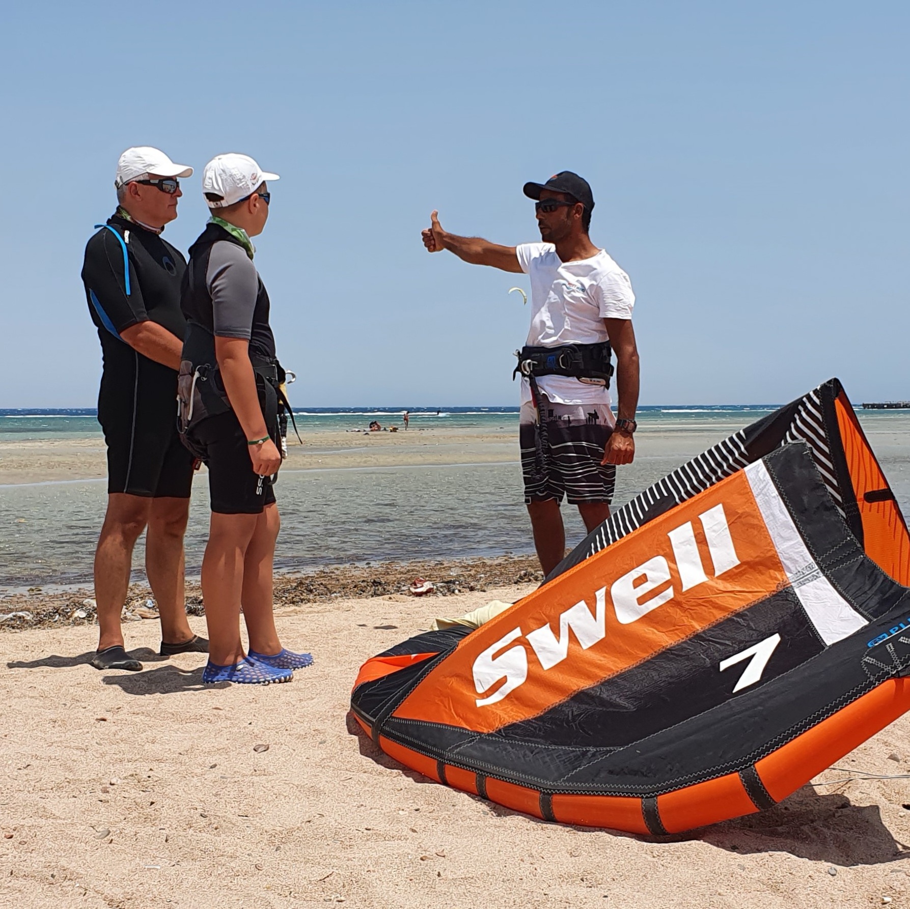 The kitesurfing school instructor runs the DUO course and shows his students the sign "OK to Launch"