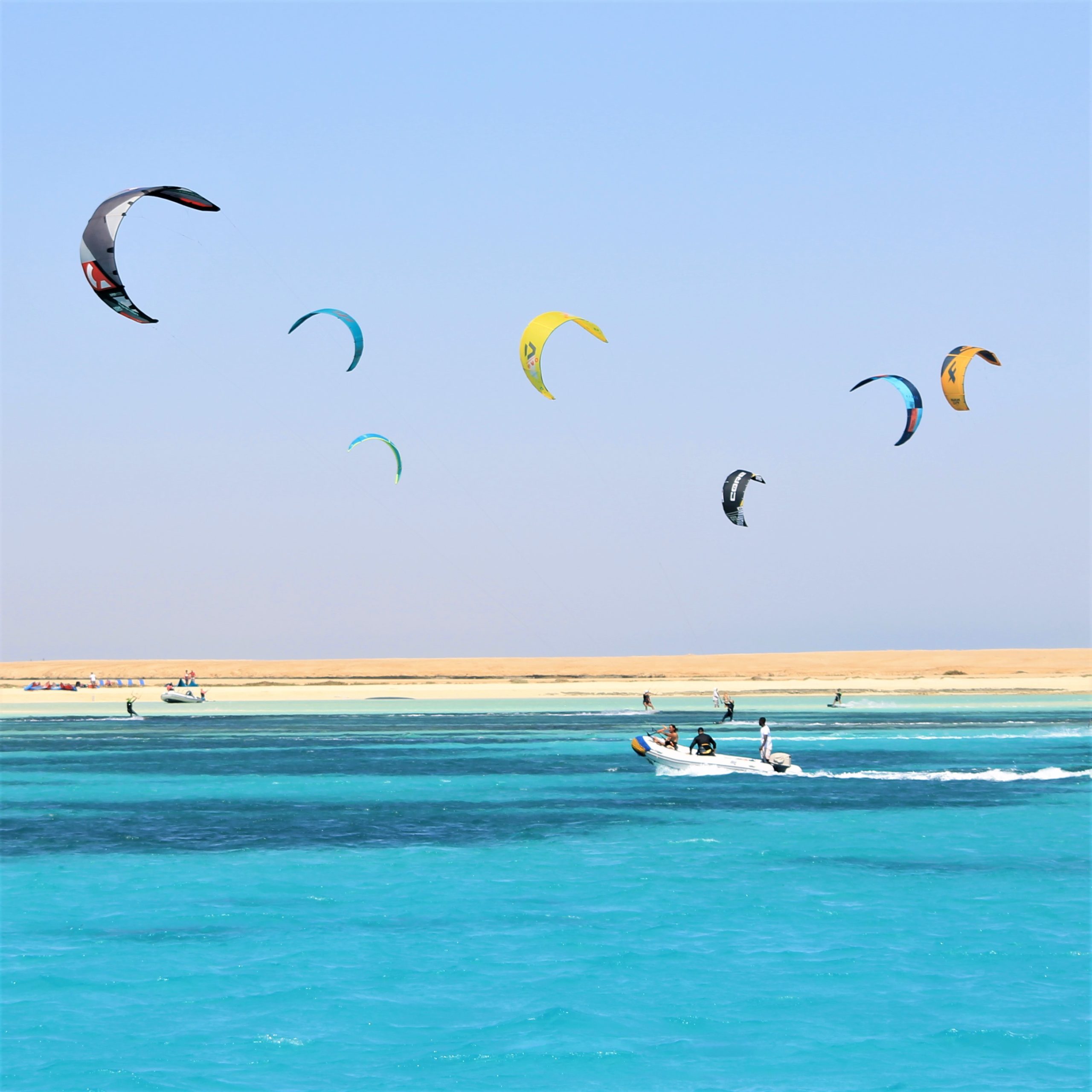 Kite safari Hurghada. Lots of kiters riding in front of an island. Rescue boat is ready for help.