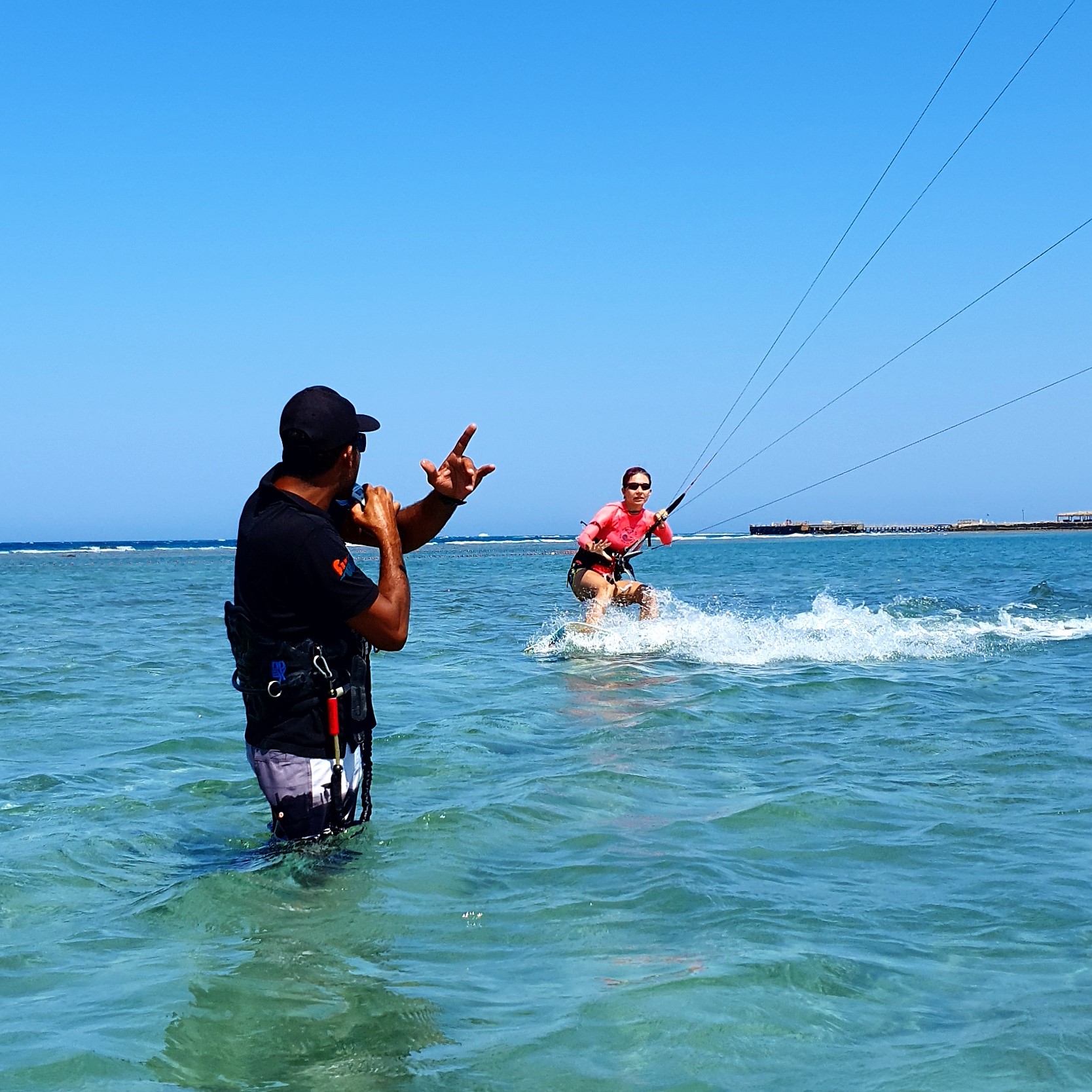 The instructor is using a radio for instructions during a kitesurfing beginner course